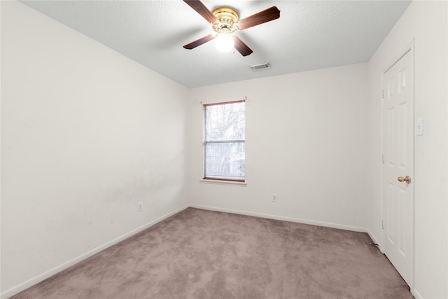 unfurnished room featuring ceiling fan, light colored carpet, and a textured ceiling