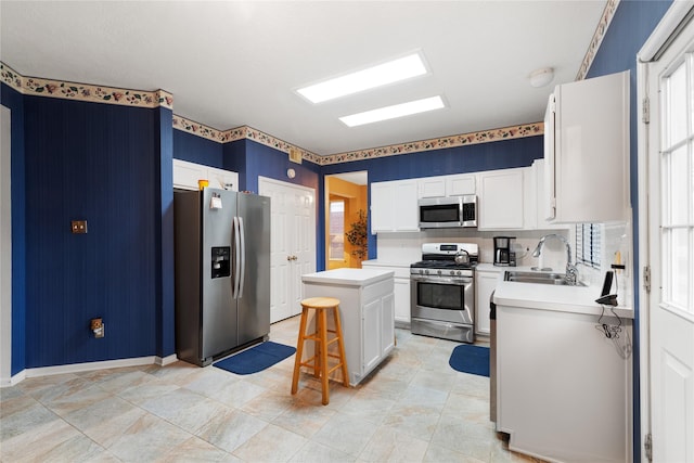 kitchen featuring white cabinetry, appliances with stainless steel finishes, sink, and a kitchen island