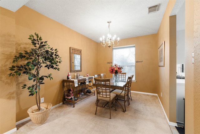 dining room with carpet flooring, a textured ceiling, and a chandelier