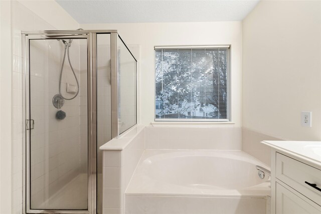 bathroom featuring vanity, a textured ceiling, and separate shower and tub