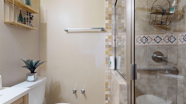 bathroom featuring vanity, a shower with door, and toilet