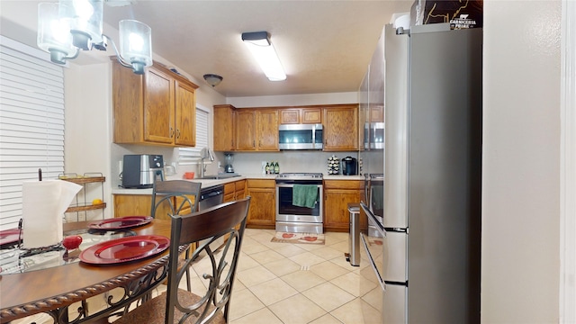 kitchen featuring light tile patterned flooring, appliances with stainless steel finishes, decorative light fixtures, and sink