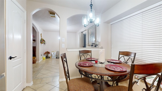 tiled dining room with an inviting chandelier