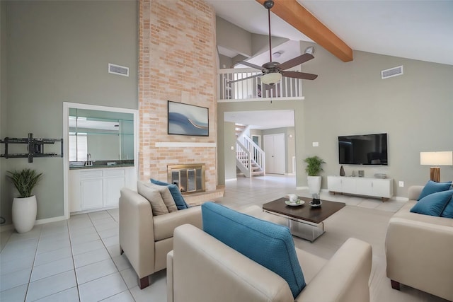 tiled living room with sink, high vaulted ceiling, a brick fireplace, ceiling fan, and beam ceiling