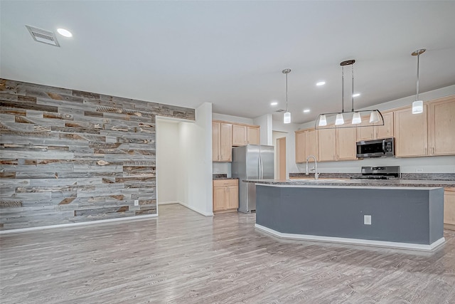 kitchen featuring light wood-type flooring, appliances with stainless steel finishes, pendant lighting, and light brown cabinets