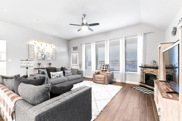 living room featuring visible vents, dark wood finished floors, lofted ceiling, a fireplace, and a ceiling fan