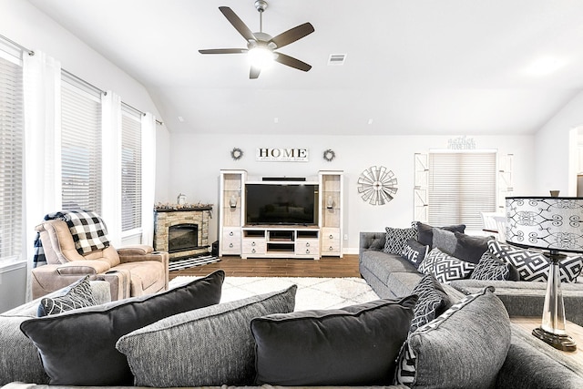 living area with visible vents, dark wood finished floors, a fireplace, ceiling fan, and vaulted ceiling