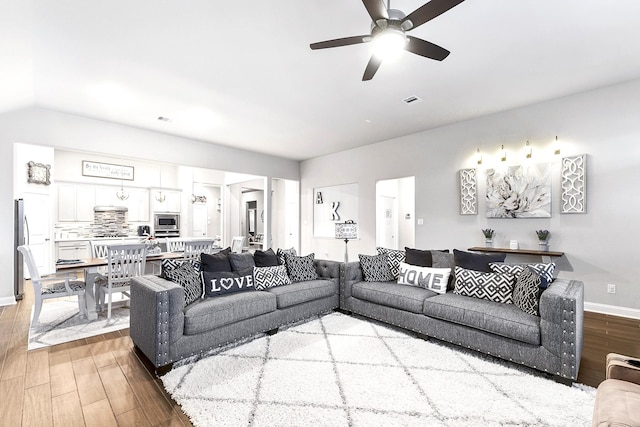 living area featuring ceiling fan, wood finished floors, visible vents, and baseboards