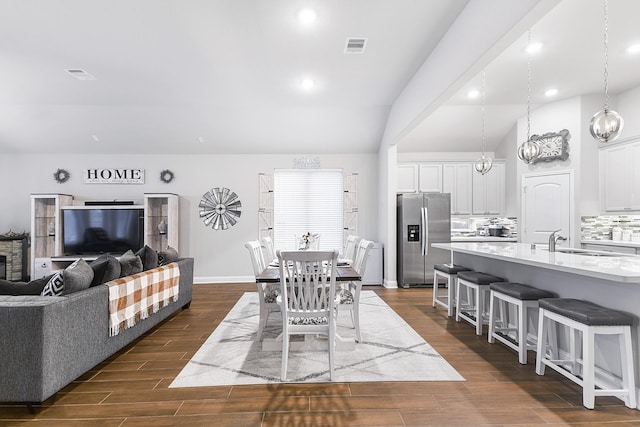 dining area featuring dark wood finished floors, visible vents, and vaulted ceiling