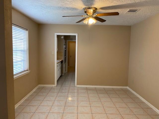 tiled spare room with a textured ceiling and ceiling fan