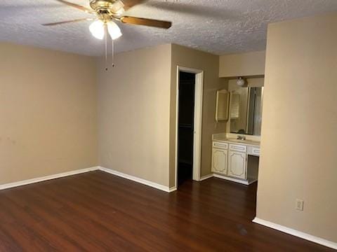 empty room with dark wood-type flooring, ceiling fan, and a textured ceiling