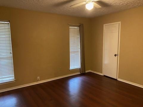 empty room with ceiling fan, dark hardwood / wood-style floors, and a textured ceiling