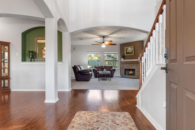 entryway with ceiling fan, dark wood-type flooring, and a towering ceiling