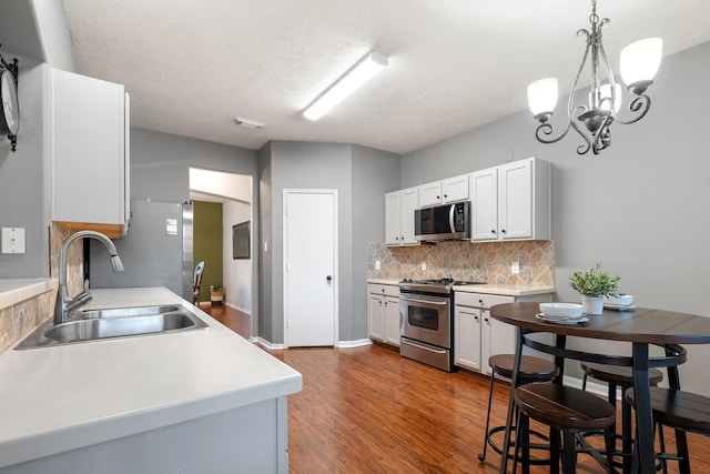 kitchen featuring white cabinetry, appliances with stainless steel finishes, sink, and hanging light fixtures