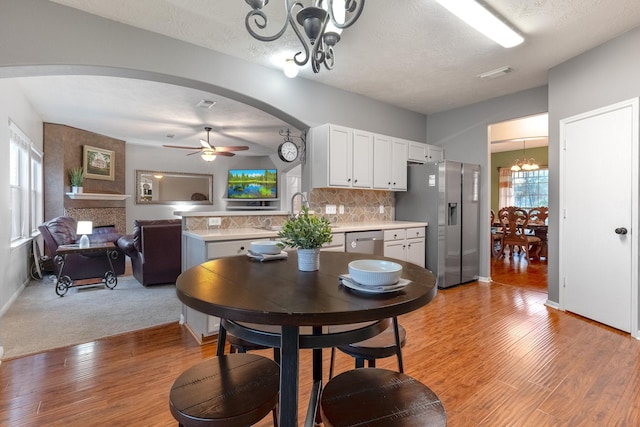 dining space featuring ceiling fan with notable chandelier, light hardwood / wood-style flooring, and a textured ceiling