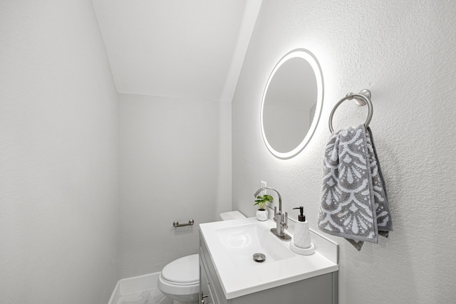 bathroom with vanity, toilet, and vaulted ceiling