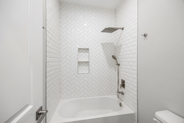 bathroom featuring toilet and tiled shower / bath combo