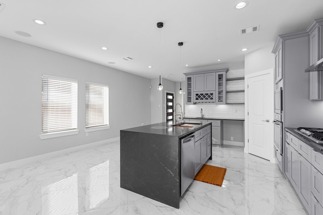 kitchen featuring gray cabinets, appliances with stainless steel finishes, decorative light fixtures, an island with sink, and sink