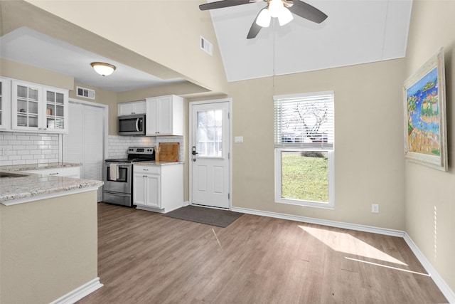 kitchen with hardwood / wood-style flooring, white cabinetry, stainless steel appliances, tasteful backsplash, and light stone countertops