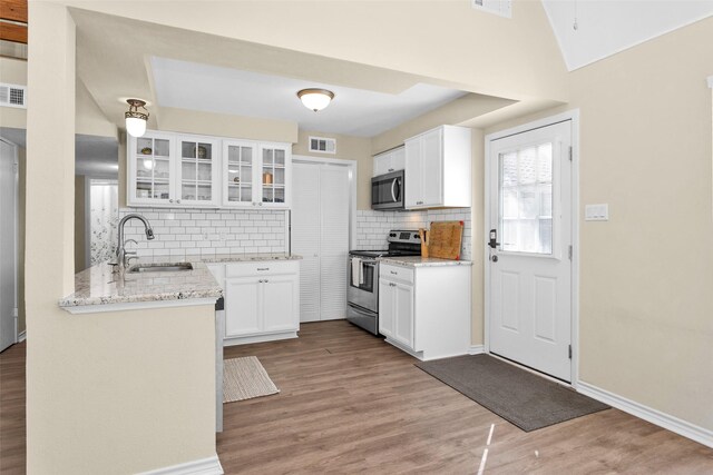 410 Indian Shr, Livingston, TX 77351 - kitchen with stainless steel appliances, decorative backsplash, white cabinetry, glass insert cabinets, and light wood-type flooring