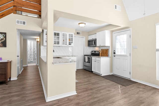 kitchen with light stone countertops, appliances with stainless steel finishes, hardwood / wood-style floors, and white cabinets