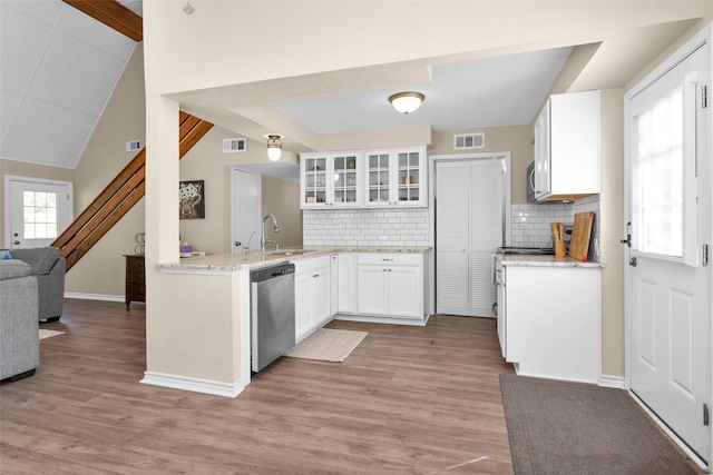 410 Indian Shr, Livingston, TX 77351 - kitchen featuring appliances with stainless steel finishes, glass insert cabinets, light wood-type flooring, decorative backsplash, and vaulted ceiling