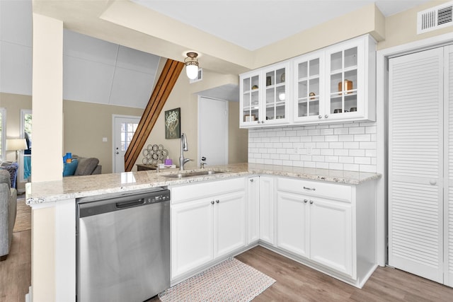 kitchen featuring sink, dishwasher, light stone countertops, white cabinets, and kitchen peninsula