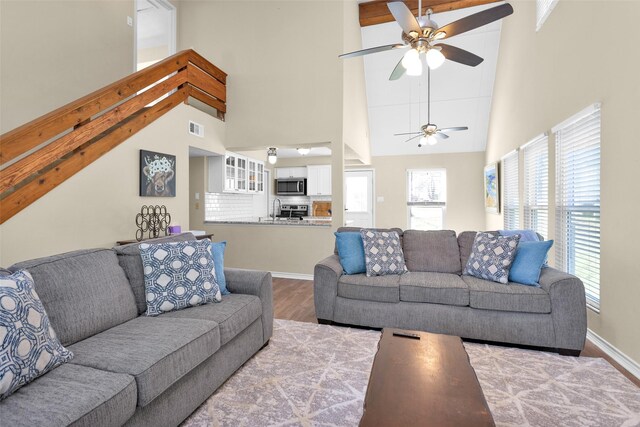 living room with sink, light hardwood / wood-style flooring, ceiling fan, and a high ceiling