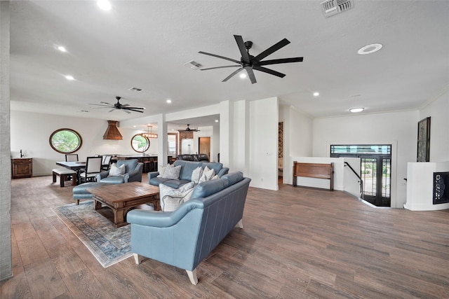 living room with ceiling fan, ornamental molding, dark hardwood / wood-style flooring, and a textured ceiling