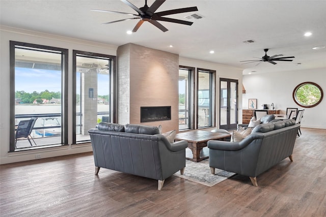 living room featuring ceiling fan, ornamental molding, a fireplace, and hardwood / wood-style floors