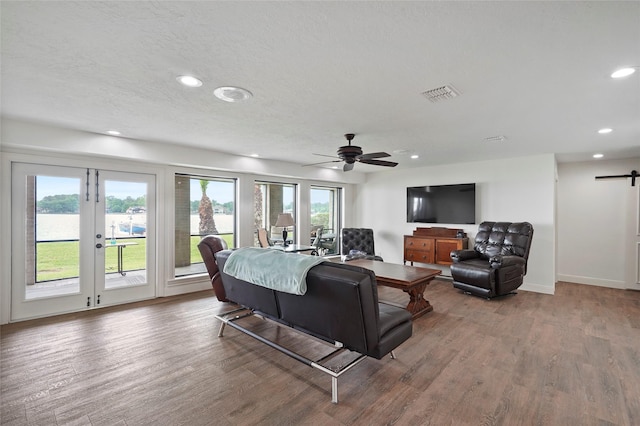 living room featuring hardwood / wood-style floors, a textured ceiling, a barn door, and a healthy amount of sunlight