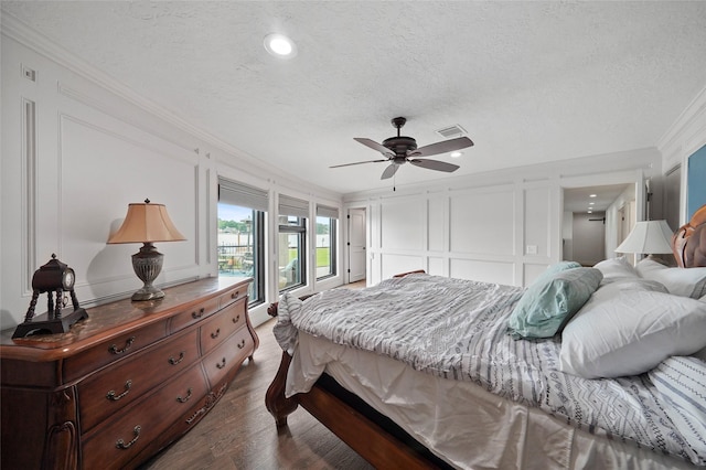 bedroom featuring ornamental molding, dark hardwood / wood-style floors, access to exterior, and a textured ceiling