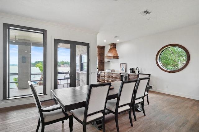 dining area with hardwood / wood-style flooring, ornamental molding, and french doors