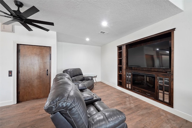 living room with hardwood / wood-style flooring, ceiling fan, a textured ceiling, and built in features