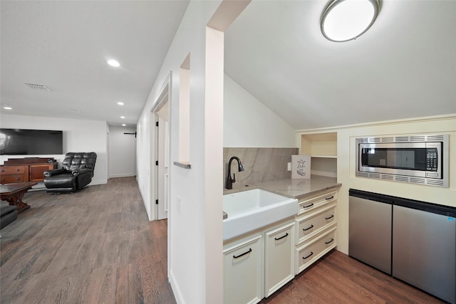 kitchen featuring lofted ceiling, sink, backsplash, hardwood / wood-style floors, and stainless steel microwave