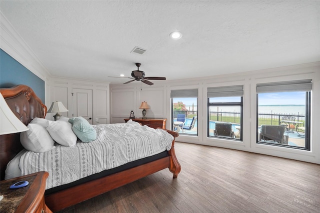 bedroom featuring crown molding, access to exterior, hardwood / wood-style flooring, and a textured ceiling