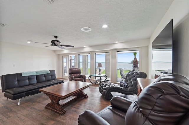 living room with a water view, dark hardwood / wood-style floors, a textured ceiling, and ceiling fan