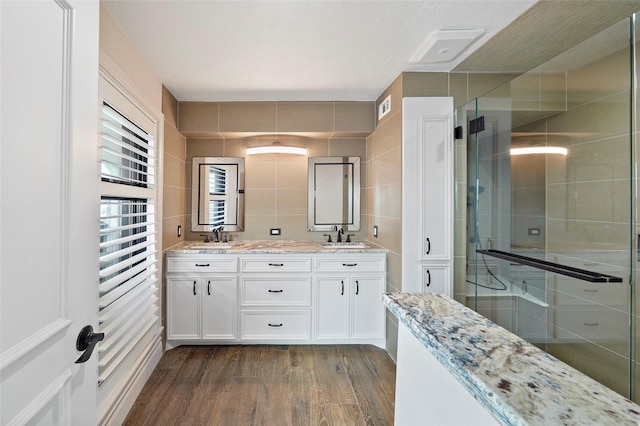 bathroom featuring tile walls, hardwood / wood-style floors, vanity, and a shower with shower door