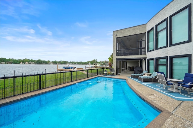 view of pool with a patio, a water view, a lawn, and a sunroom