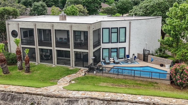 rear view of property featuring a fenced in pool, a yard, a sunroom, and a patio