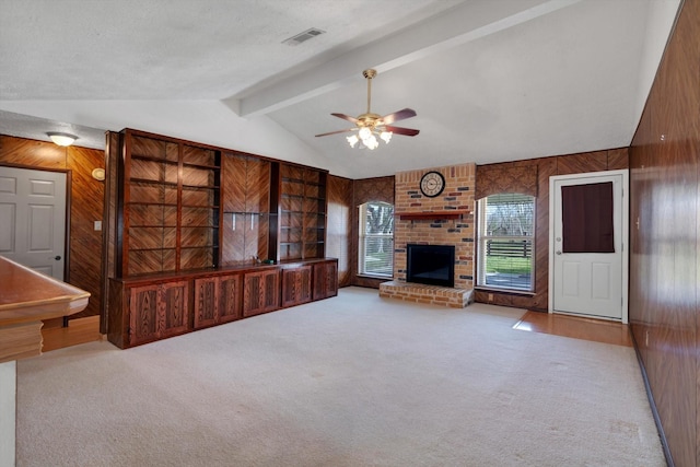 unfurnished living room with a fireplace, wooden walls, lofted ceiling with beams, and carpet