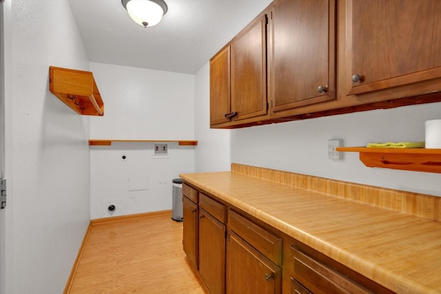 laundry room with cabinets, electric dryer hookup, hookup for a washing machine, and light wood-type flooring