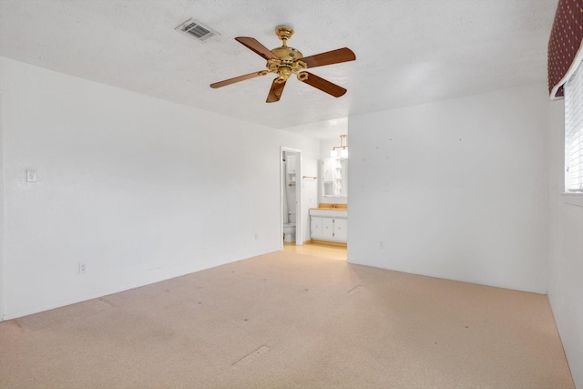 empty room with a textured ceiling, light colored carpet, and ceiling fan