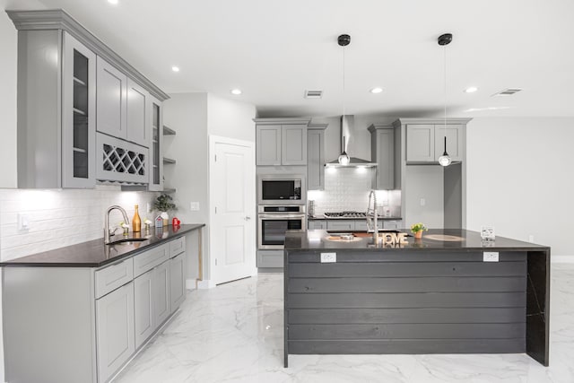 kitchen with gray cabinets, sink, hanging light fixtures, stainless steel appliances, and wall chimney range hood