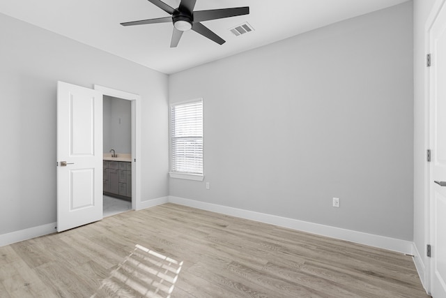 unfurnished bedroom featuring connected bathroom, sink, ceiling fan, and light wood-type flooring