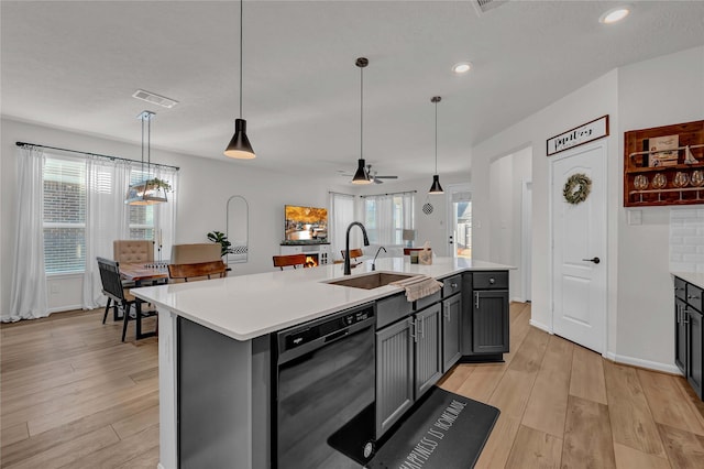 kitchen featuring sink, gray cabinetry, hanging light fixtures, a center island with sink, and dishwasher