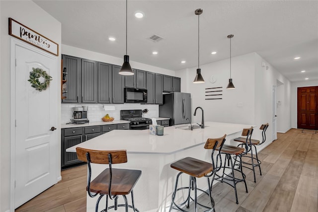 kitchen featuring gray cabinets, a breakfast bar, sink, black appliances, and a spacious island