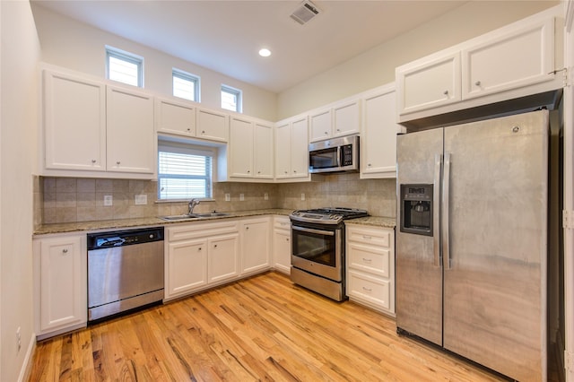 kitchen with sink, light hardwood / wood-style flooring, stainless steel appliances, light stone countertops, and white cabinets