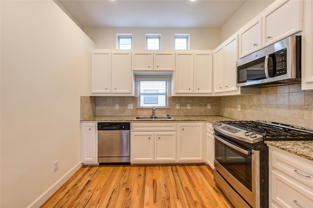 kitchen featuring white cabinetry, sink, stainless steel appliances, and light stone countertops