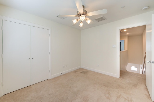 unfurnished bedroom with light colored carpet, a closet, and ceiling fan